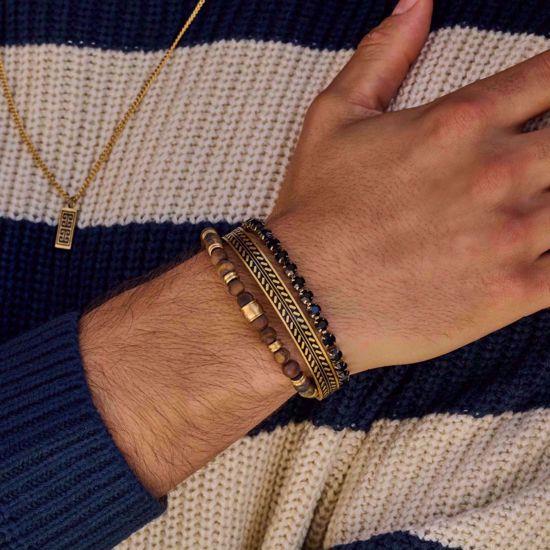 Frank IP guld stål armbånd med sort mønsterindlæg på håndled, sammen med andre armbånd.